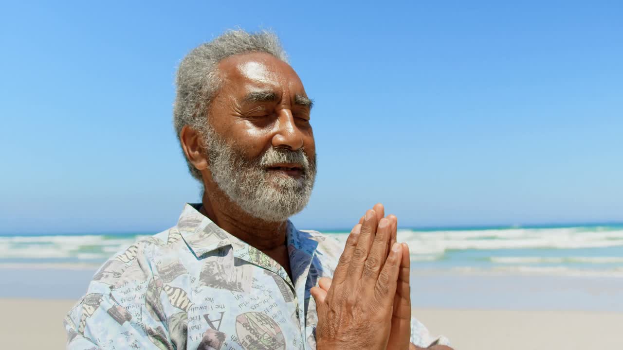 Front view of active senior African American man performing yoga on the beach 4k