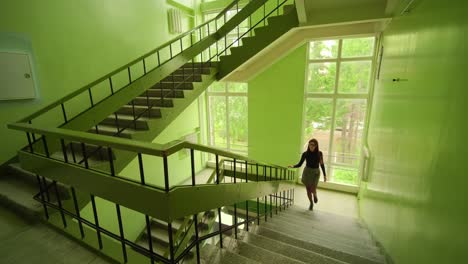 woman running up stairs in a green building interior