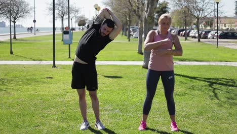 Two-sportsmen-warming-up-before-morning-workout-in-park.