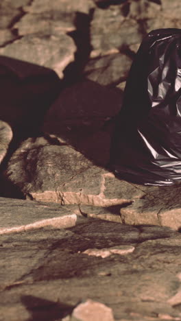 a black trash bag sits on a rocky surface