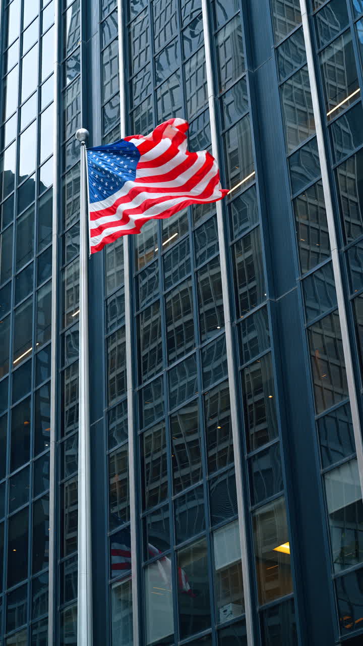 Bandiera americana che sventola su un'asta di fronte a un grattacielo di vetro. Bandiera degli Stati Uniti su asta d'argento contro la facciata di un edificio per uffici in vetro blu nel distretto finanziario di Manhattan, New York.