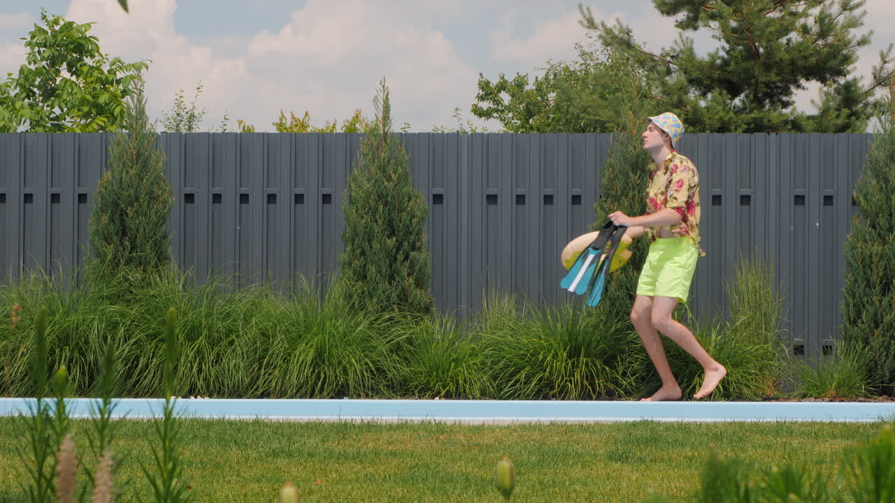 Man with swimming pool accessories walks along pool edge