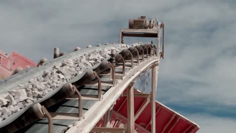 conveyor-belt-of-a-stone-crusher-carrying-rocks-to-be-crushed-with-a-sky-with-clouds-in-the-background