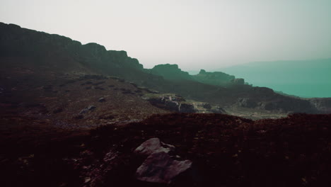 a view of a rocky mountain with a body of water in the distance mountain path