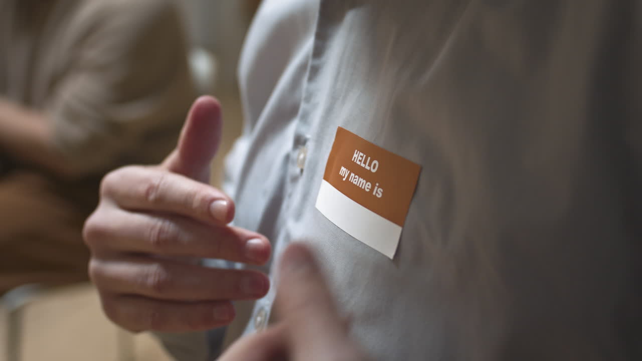 Close Up of Man Attaching Name Tag on Shirt at Support Group Meeting