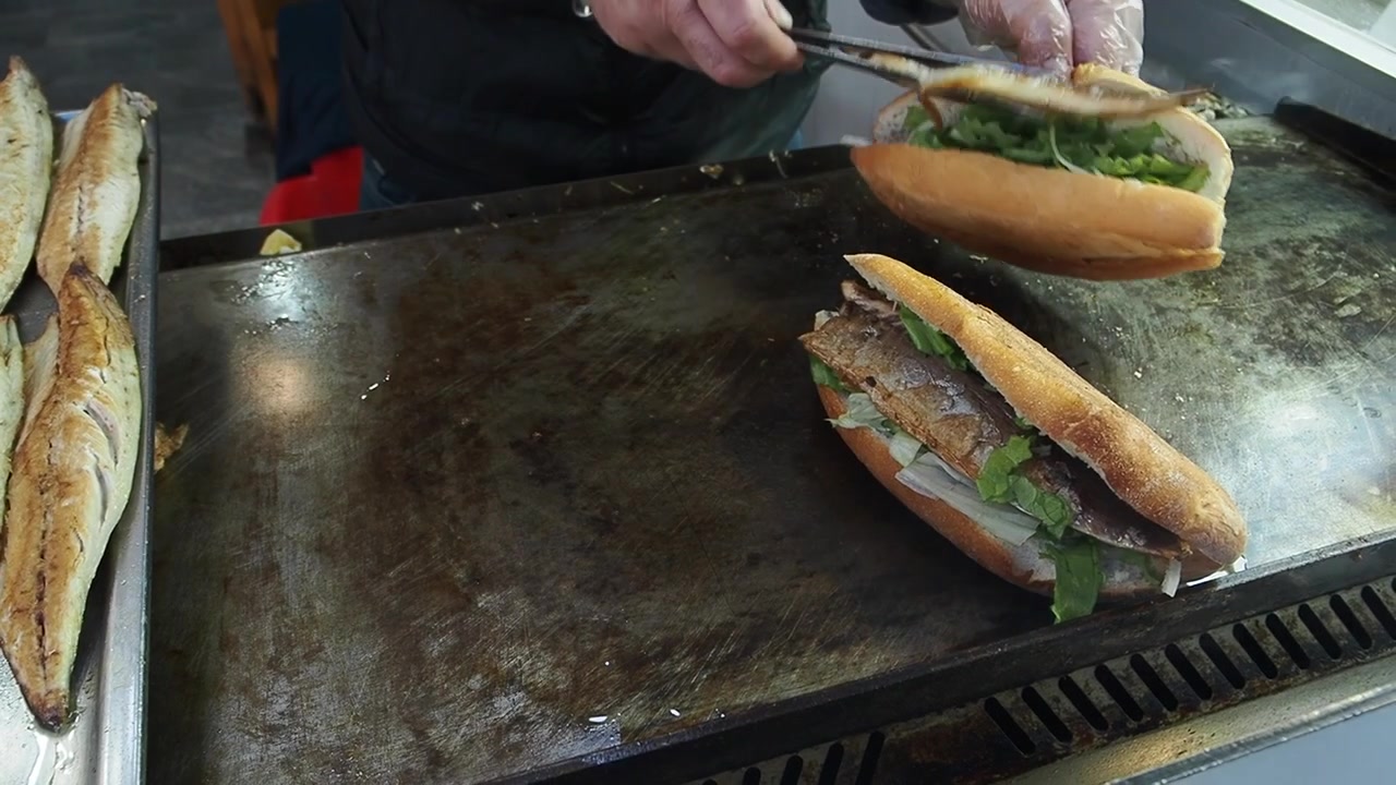 Chef che prepara panini di pesce tradizionali turchi su una griglia calda