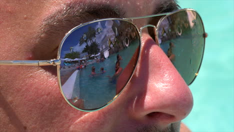 escena de personas en la piscina reflejada en lentes de gafas de sol