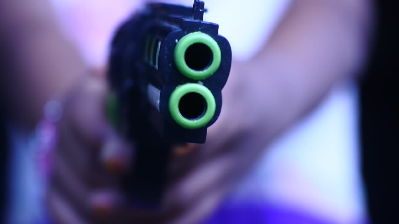 someone pointed a toy gun. focus on gun. close-up shot