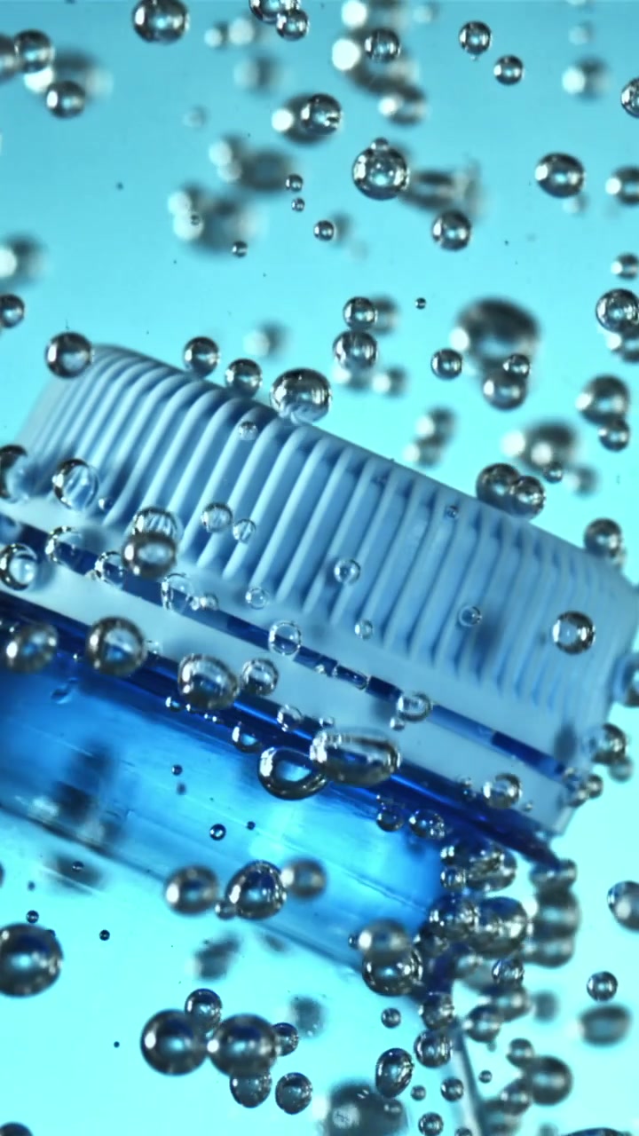 Blauer Plastikflaschendeckel im Wasser mit aufsteigenden Blasen
