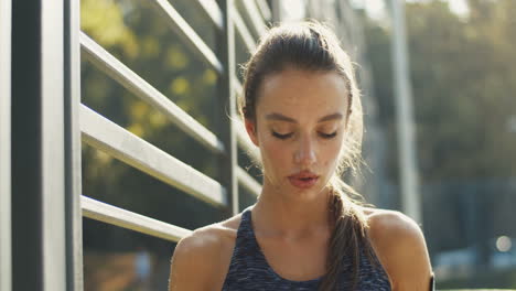 mujer deportiva cansada parada en una cancha al aire libre, descansando y bebiendo agua fría después del entrenamiento 1