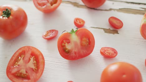 Vídeo-De-Tomates-Rojos-Frescos,-Cortados-A-La-Mitad-Y-Enteros,-Sobre-Fondo-Rústico-Blanco