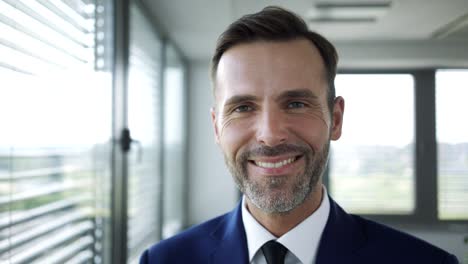 confident handsome businessman looking out the window and then smiling at camera