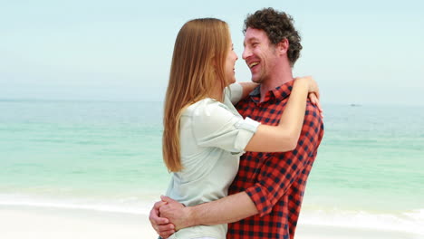 una pareja feliz abrazándose en la playa.