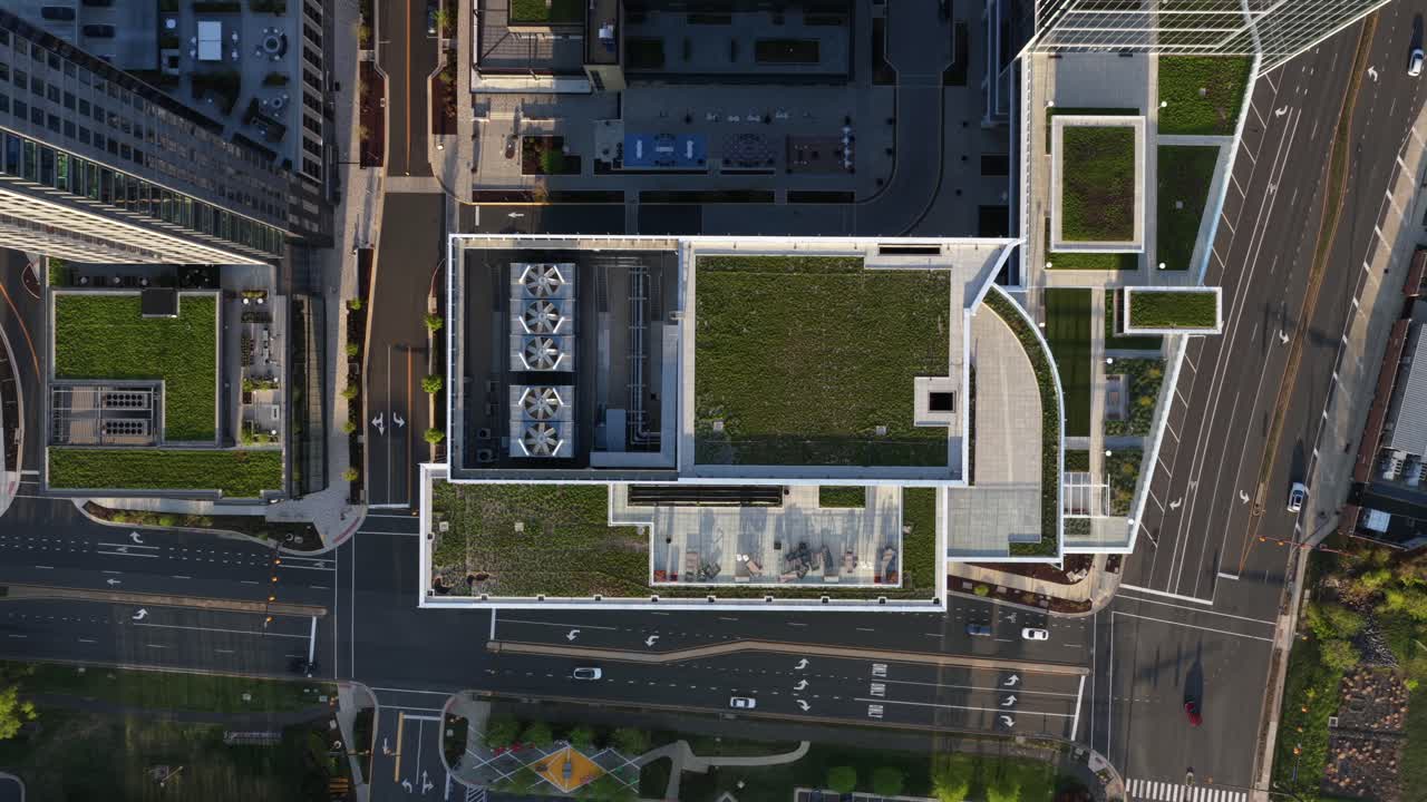 Modern downtown buildings with green rooftop gardens, ventilation systems and intersecting streets, showing sustainable urban design in warm sunlight. Aerial top down flyover. Esg theme