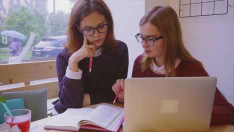 dos chicas adolescentes estudiando juntas en un café