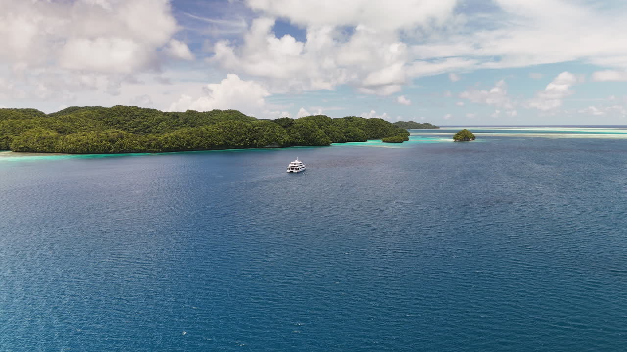Impressive cinematic flyover scanning and revealing the serene turquoise coastline and small tropical islands of Palau. With a yacht in the water