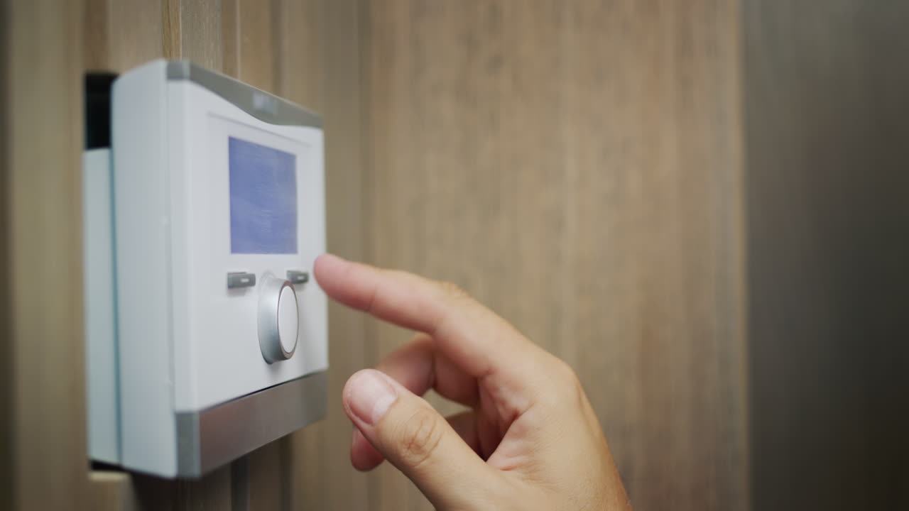 el propietario regula la temperatura de la casa en el panel de control electrónico