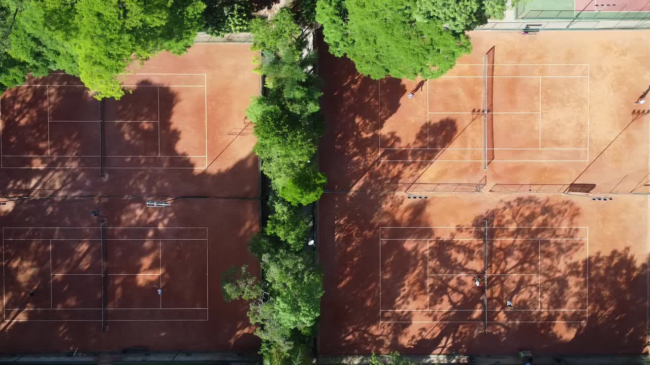 viaggiando a lato con un drone che filma bellissimi campi da tennis in mezzo agli alberi e alla natura, l'alba, la luce dolce