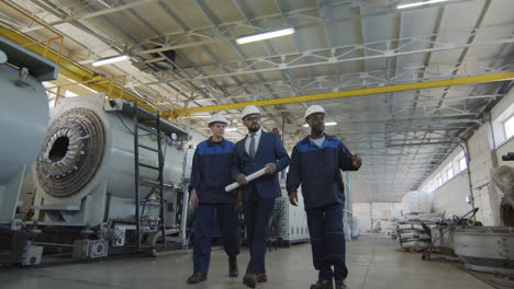 male manufacturing engineer and workers walking through plant