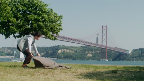 woman kneeling in park by a bridge