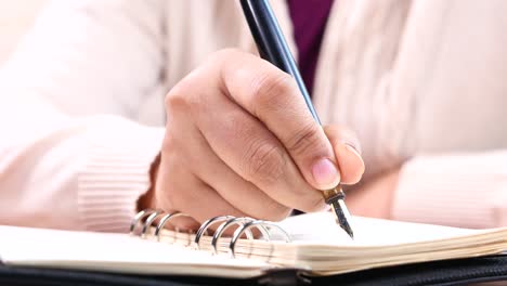 person writing in a notebook with a fountain pen