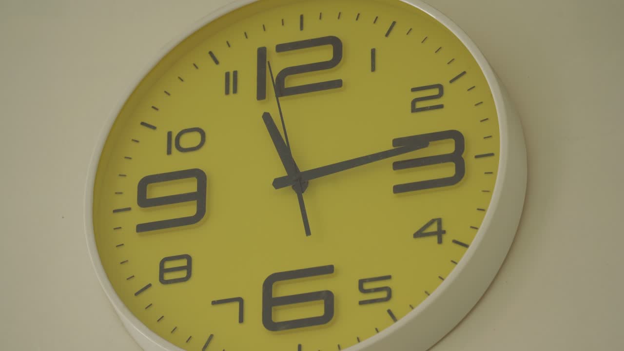 Orologi da ufficio su parete gialla.