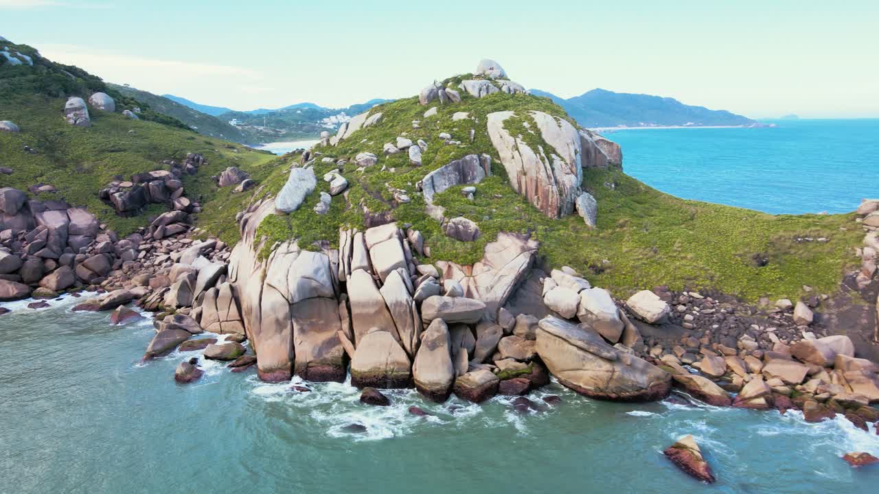 Aerial view of the rocky shore of Gravata Beach in Florianopolis, Santa Catarina, Brazil, with a dragon's head full of rocks, nature, and abundant Atlantic Forest with a turquoise ocean