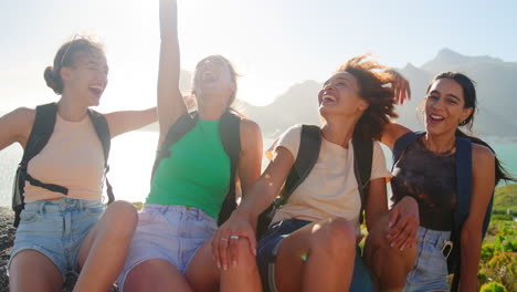 Portrait-Of-Female-Friends-With-Backpacks-On-Vacation-Taking-A-Break-On-Hike-Through-Countryside