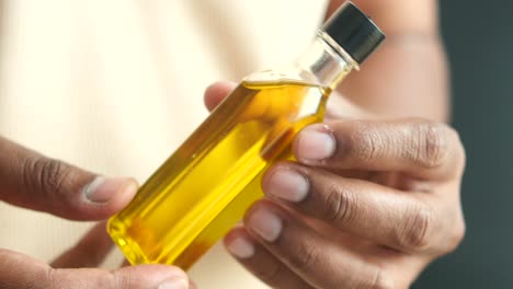 persona sosteniendo una pequeña botella de aceite amarillo
