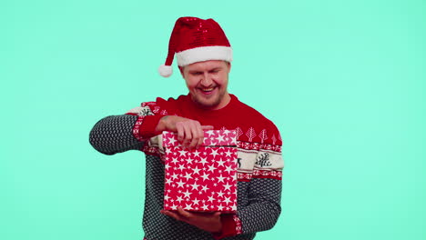 Mann-Mit-Weihnachtlicher-Roter-Pullovermütze-Lächelt,-Packt-Geschenk-Aus,-öffnet-Schachtel-Mit-Hauskatze,-Tolle-Überraschung