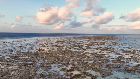 Flying-Above-Tidal-Flats-Toward-Distant-Ship-On-The-Sea-At-Sunrise