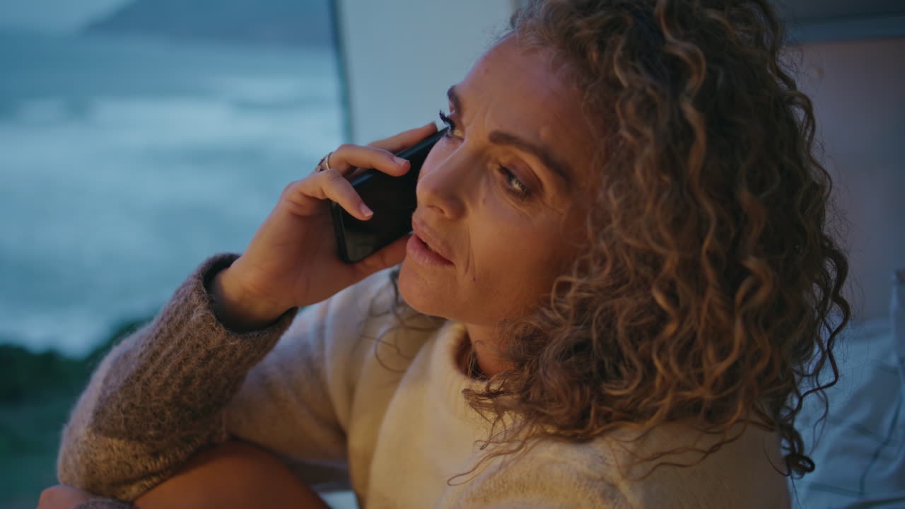 Excited woman talking mobile phone in evening campervan closeup. Lady calling