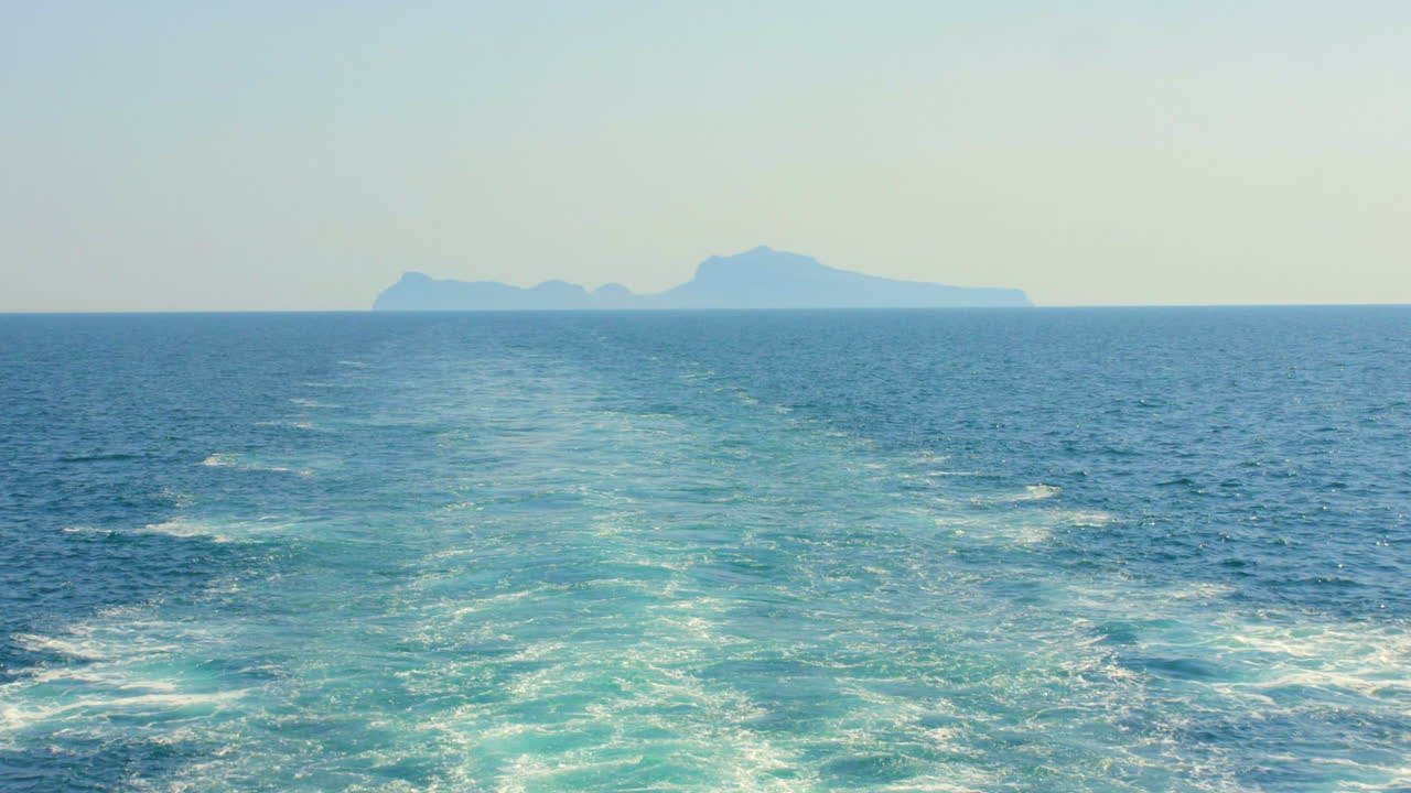 View of the sea waves crashing from a sailing ship with Capri island in the background, Italy, HD video