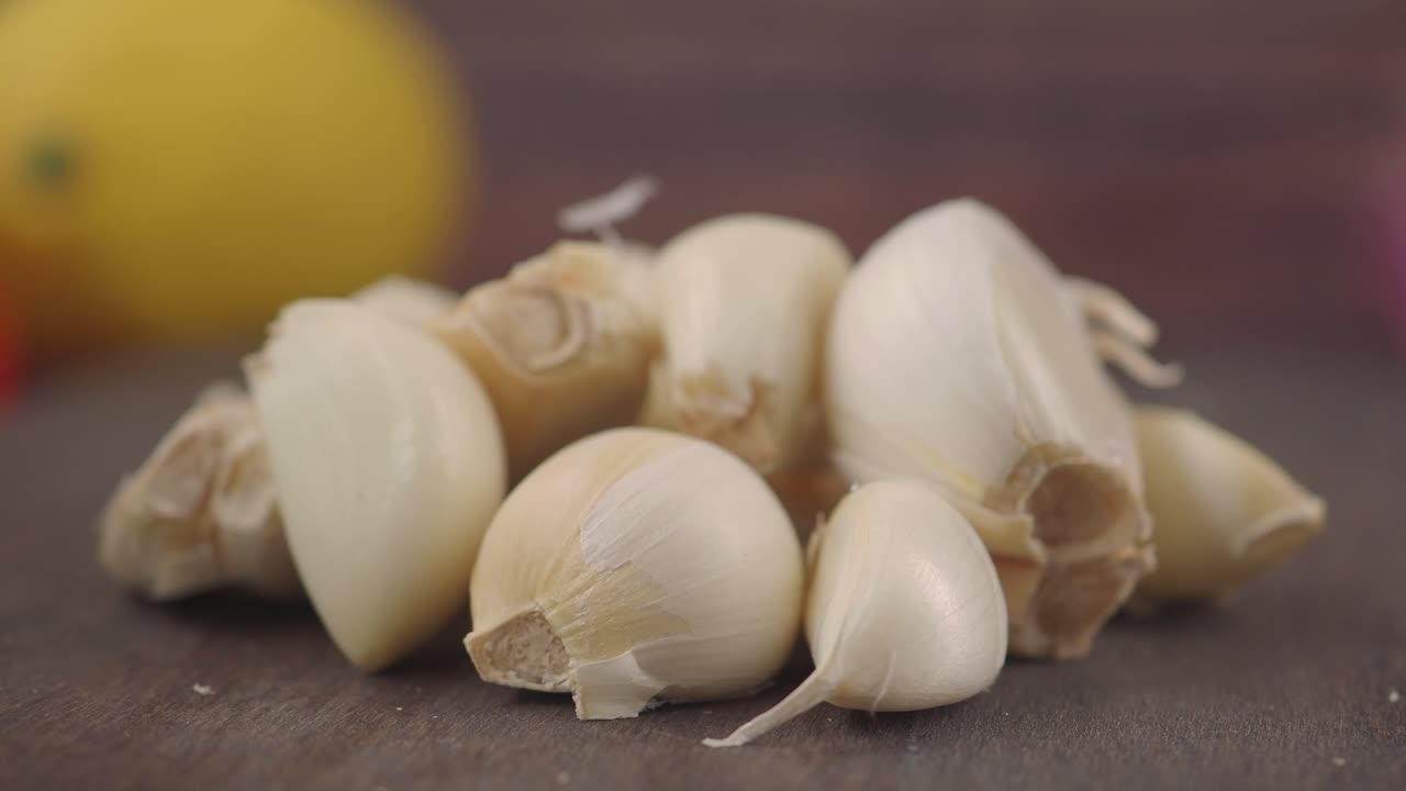 Dientes de ajo frescos sobre una superficie de madera con limón al fondo