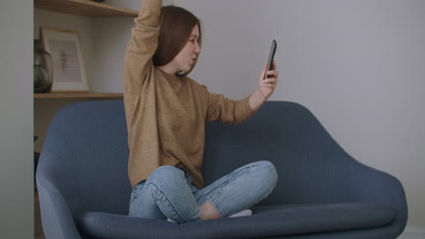 business woman typing message on mobile phone at home office. young girl chatting on phone in slow motion. close up young woman hands using smartphone on couch.