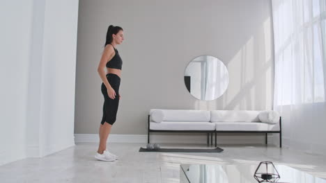 mujer deportiva alegre haciendo estampadas laterales. mujer deportiva feliz de mediana edad sala de estar haciendo estampidas laterales y sonriendo hacia adelante mientras entrena