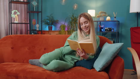 Young-woman-relaxing-interesting-book-turning-pages-smiling-enjoying-literature-taking-rest-on-sofa