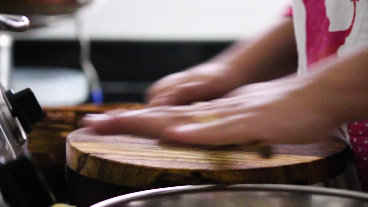 Close-up of hands skillfully rolling out dough to make traditional Indian roti or chapati on wooden board. Captures authentic home cooking, culinary traditions and fresh food.