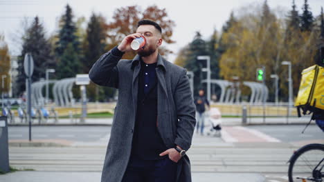 businessman holding coffee cups on street. man walking the street with cup of coffee