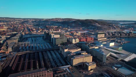 aerial drone pan shot over oslo central train station alongside sea in sentralstasjon, norway during morning time