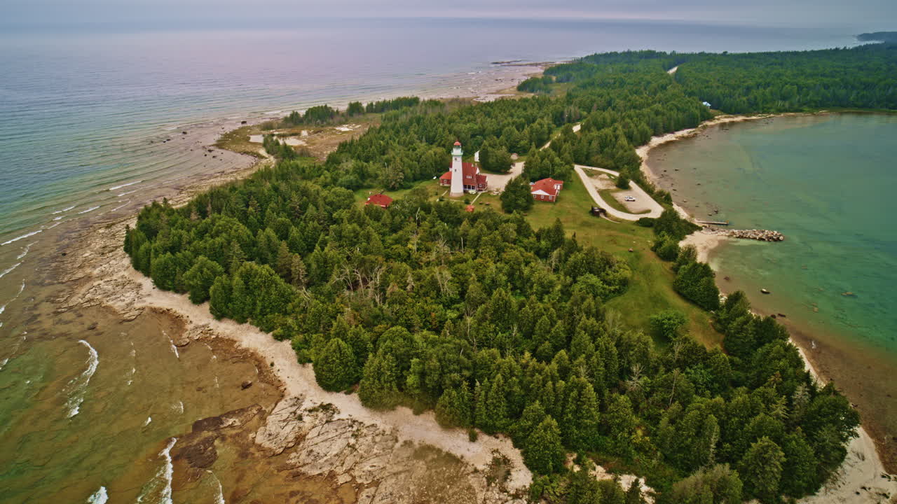 Drone shot flying backwards to reveal lighthouse on island