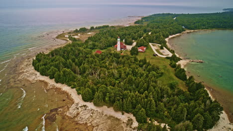 drone shot flying backwards to reveal lighthouse on island