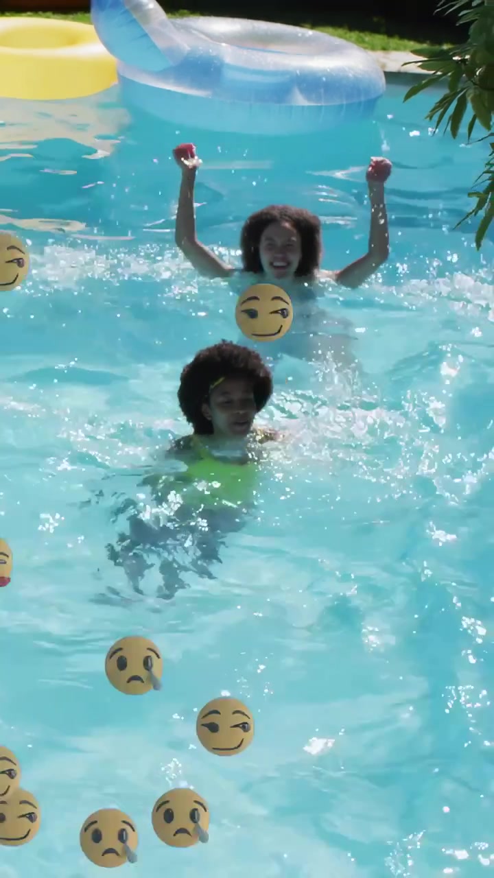 Vertical video: Two women swimming in pool splashing and reaching, making emoji float for leisure