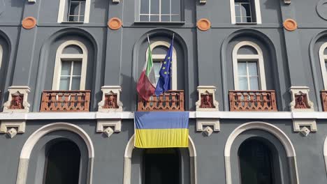 ukrainian national official flag and italian and europe flags are waving in the wind from the balcony historical building in italy