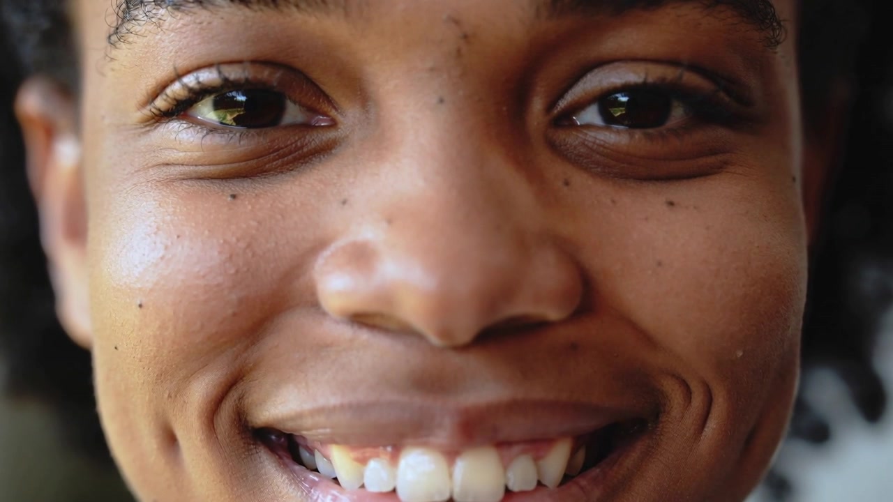 Camera starting, smiling woman shifting lips and jaw in studio close-up, showing dimples and teeth
