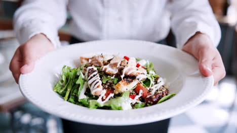 Cerca-De-La-Camarera-Del-Restaurante-Sosteniendo-Un-Plato-De-Pollo-Con-Ensalada