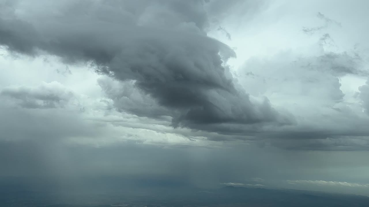 스페인의 마요르카 섬 위를 날아다니는 비행기 조종실에서 찍은 극적인 폭풍우 하늘, 비가 내리는 모습