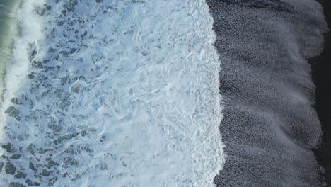 Flying-low-above-incoming-waves-leaving-patterns-on-stony-beach---Canterbury-Bight,-New-Zealand