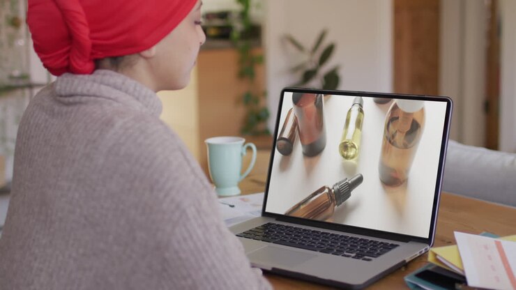 Kvinde af blandet etnicitet ved bord bruger bærbar computer, handler skønhedsprodukter online, i slow motion.