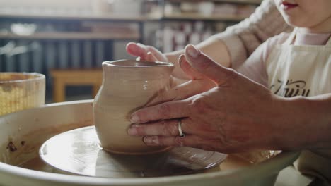 grandmother teaches her granddaughter working on a pottery rotating wheel